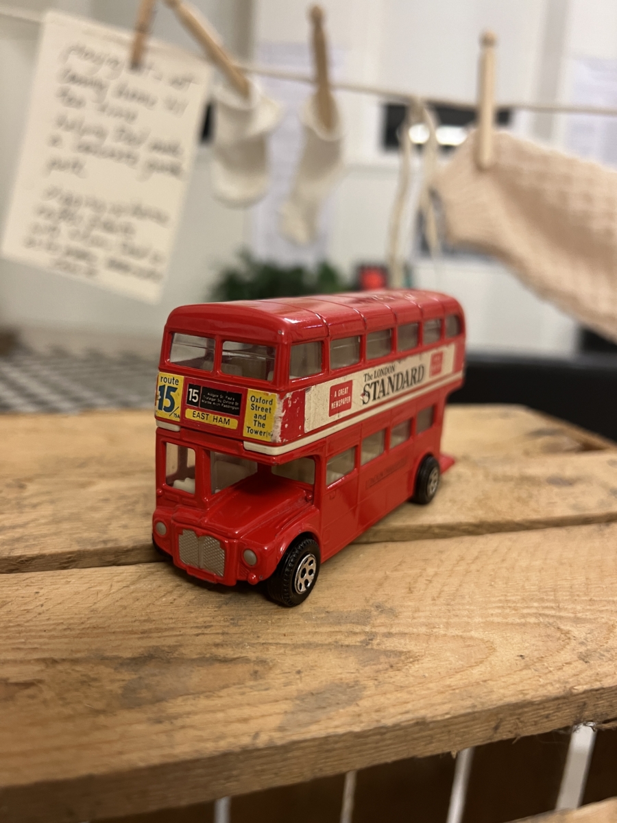 A red diecast toy London bus says 'East Ham' on the destination display above the window.