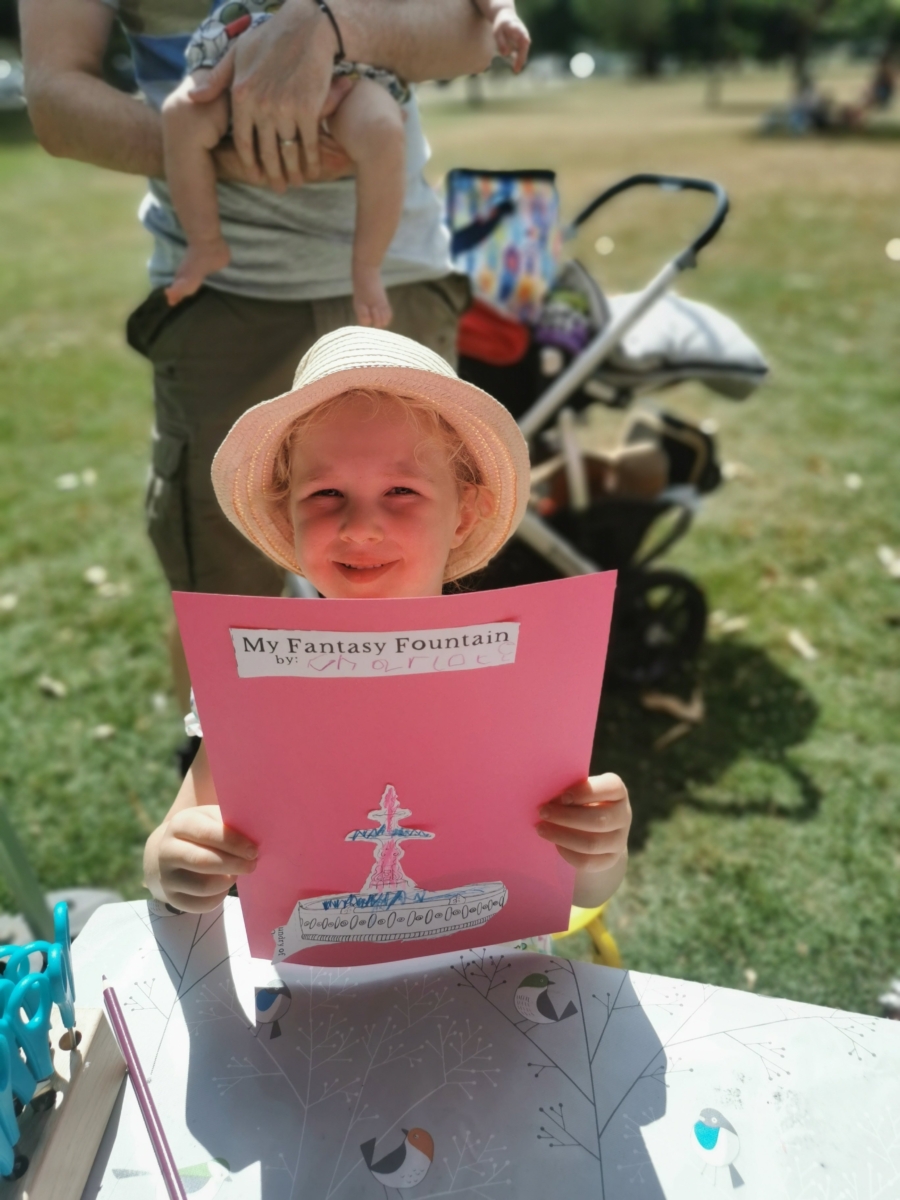 This image shows a child holding a finished 'Create your own Fantasy Fountain' game. She made it on the premiere day of Fantasy Fountain in Victoria Park, 2022.