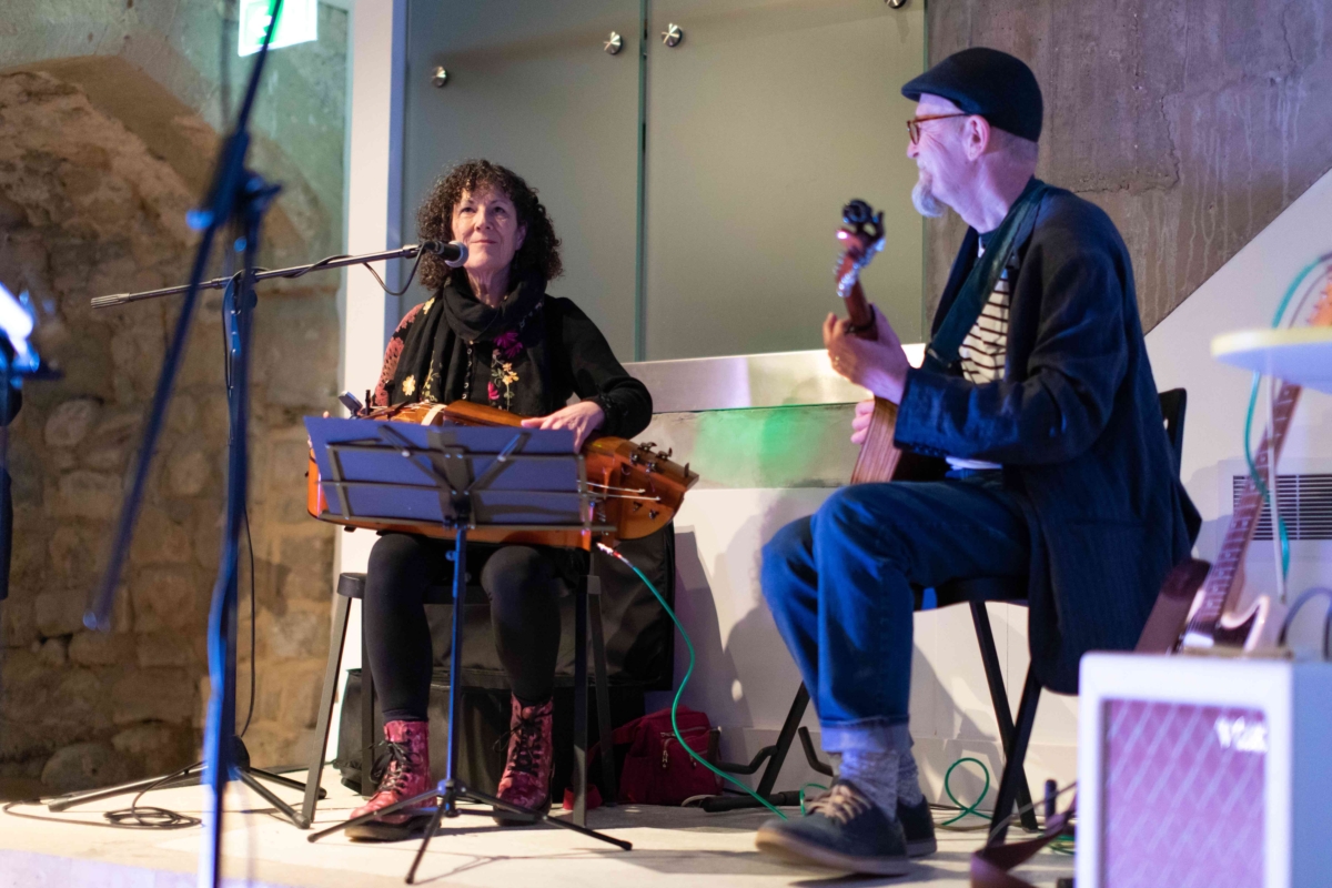 This image shows traditional folk dance interpretation by duo Su Eaton and Martin Bridle playing their own interpretation of When I Grow Up I Want To Be A Ship at the launch event in 2022. Sue is singing and playing a hurdy gurdy. Martin is playing guitar. 