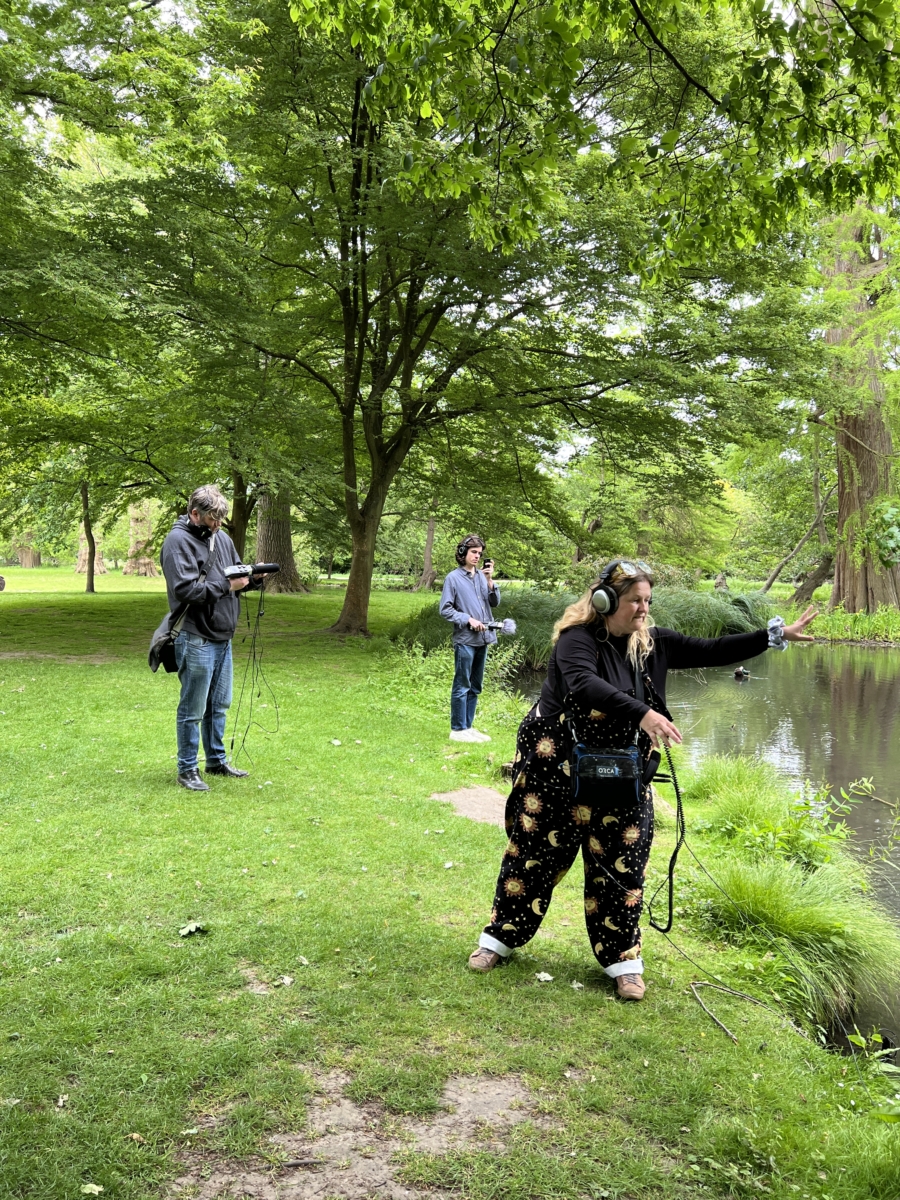 Sounds of the Subaquatic in The Royal Parks, London, led by sound artist Emily Peasgood, 2023. Emily Peasgood is throwing a hydrophone into a river in Bushy Park. Sam Slattery (guest artist) and Henry McLean (student from Guildhall School of Music and Drama) are in the background.